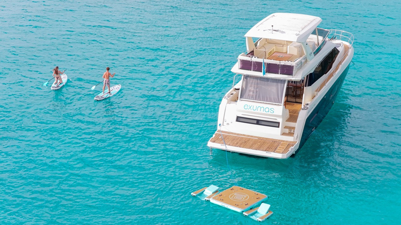 Guests paddleboarding beside a yacht at the sandbar